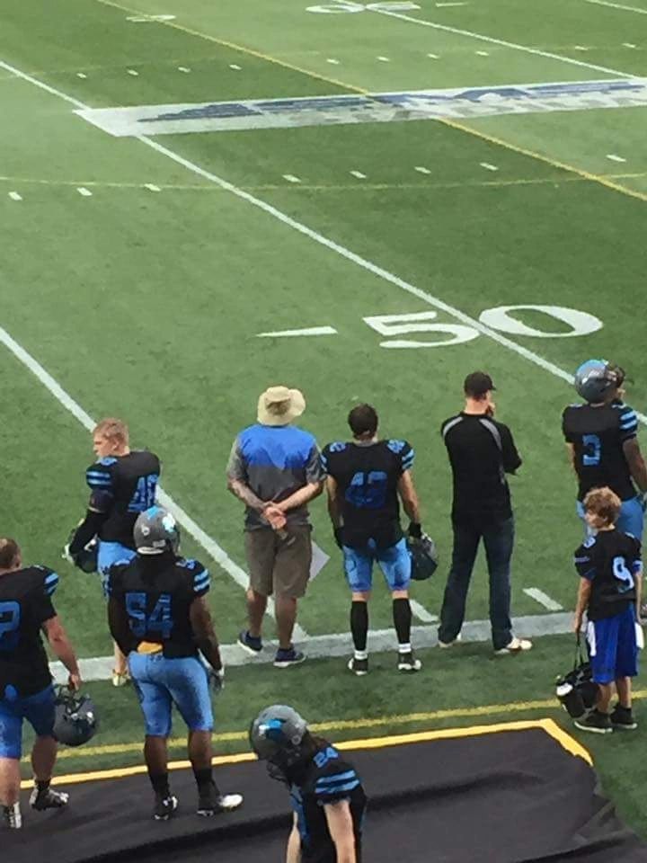 Monarchs players and coaches at the 50-yard line before kickoff
