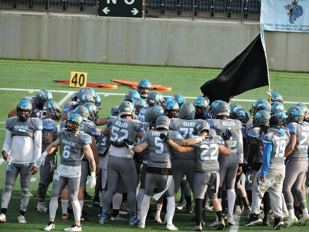 Monarchs team huddle at the 40-yard line with Monarchs banner