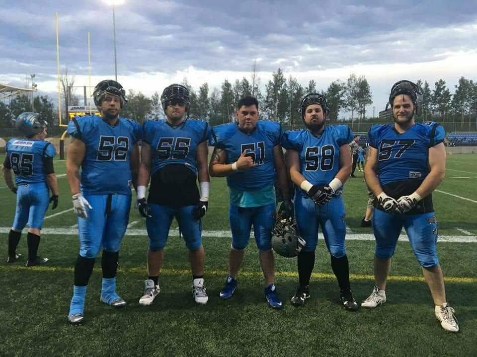 Monarchs offensive linemen posing in blue jerseys at SMS Stadium