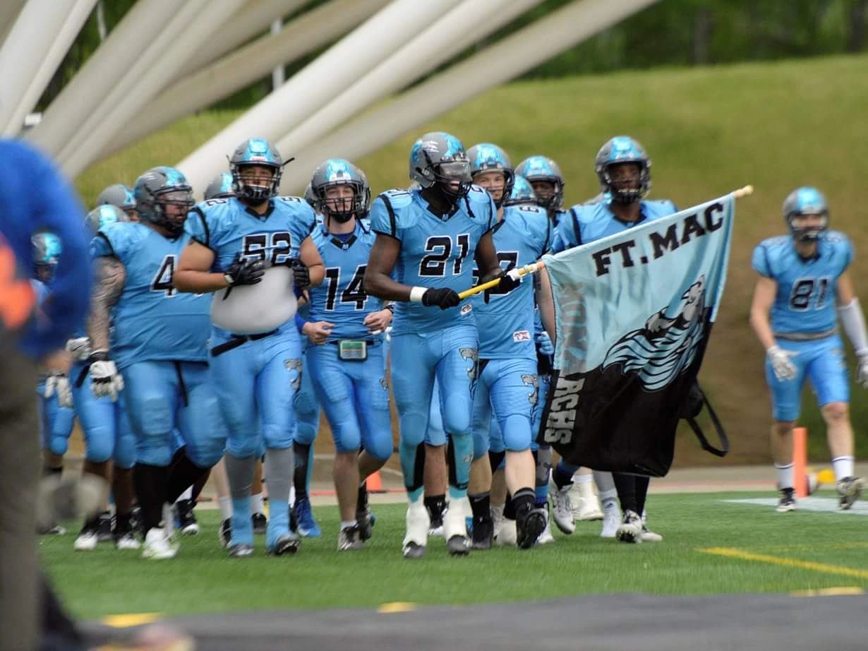 Monarchs players walking onto the field behind the FT. MAC flag
